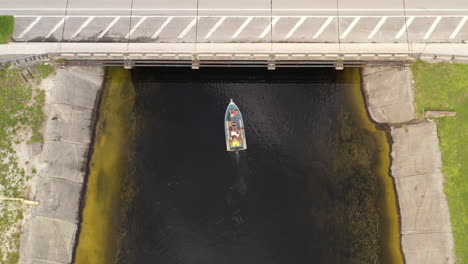 a top down drone shot over a boat in a canal on a cloudy day