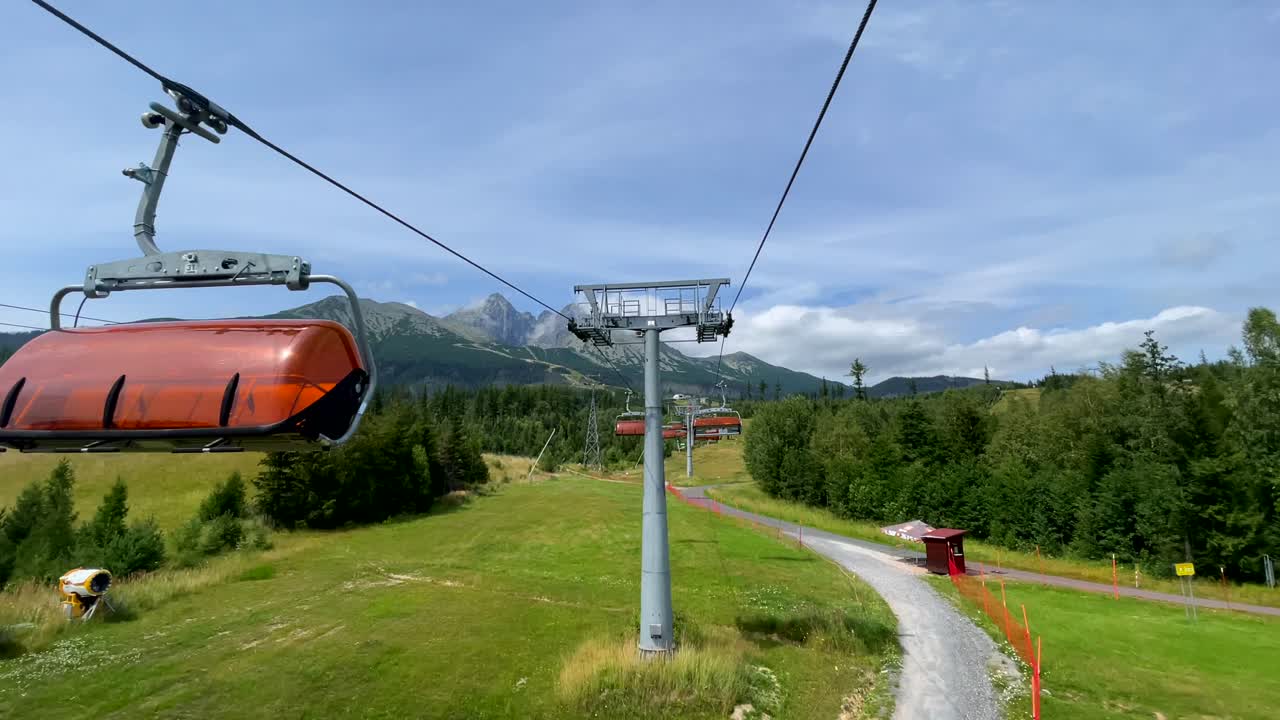 Chair lift over green forested landscape, High Tatras background, Slovakia