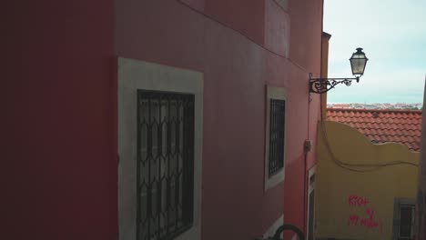 lisbon old street alley with ancient lantern, graffiti wall and city roof view