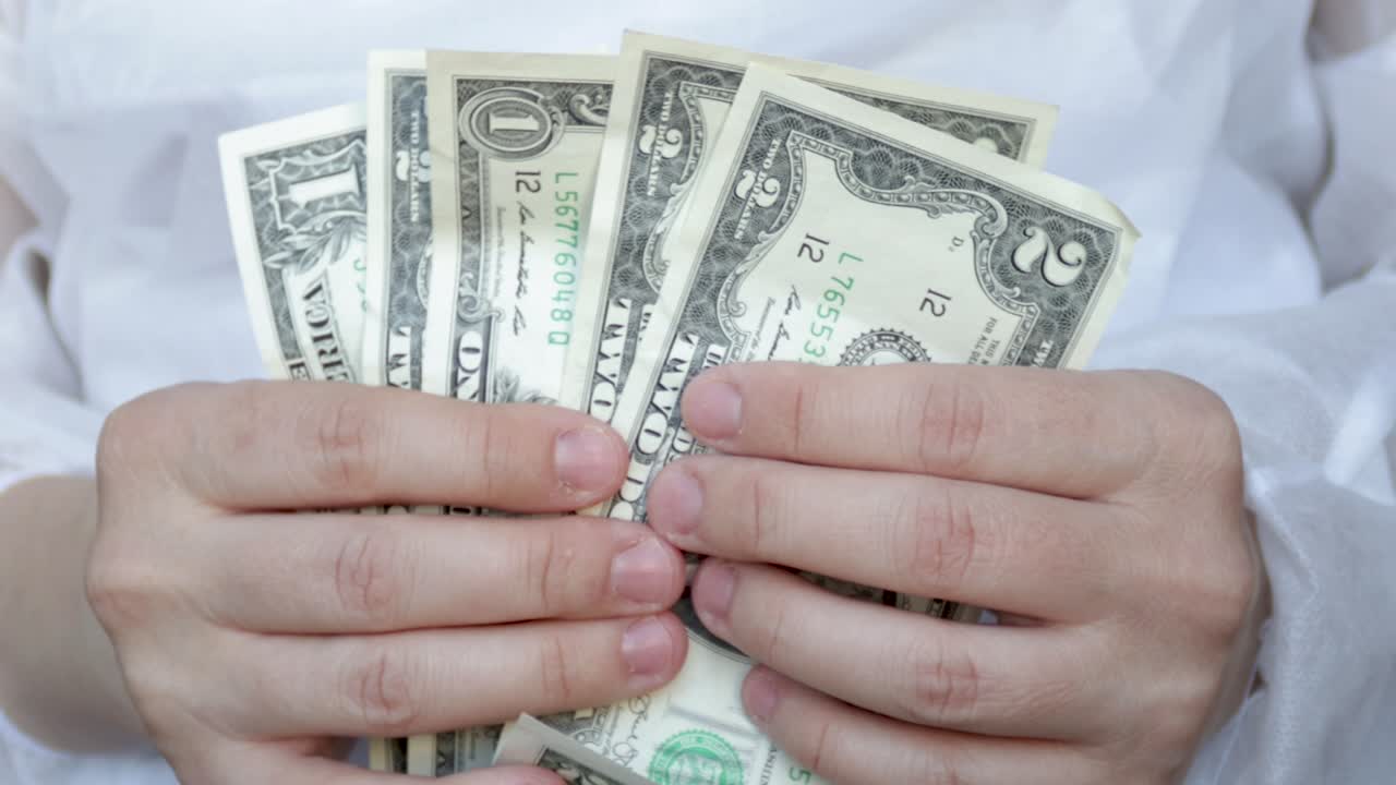 의사나 간호사가 달러 지폐를 세고 있습니다.