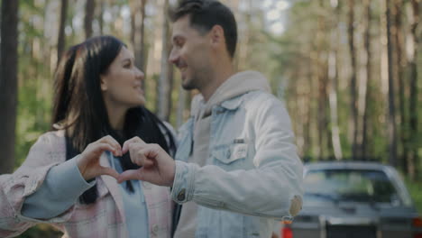 couple making heart shape with hands in the forest