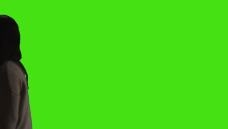 mujer joven con gafas caminando a través del cuadro contra el fondo de la pantalla verde con iluminación de baja clave