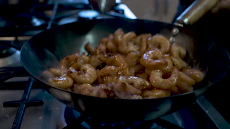 frozen prawns covered in spices being heated and stirred and wok in kitchen