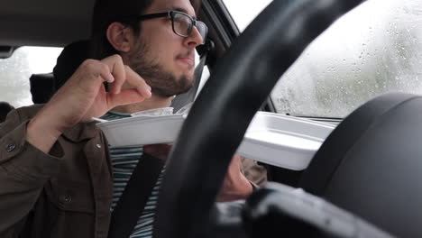 Hombre-En-Cámara-Lenta-Comiendo-Para-Llevar-En-Su-Auto-Solo,-Mirando-Hacia-Afuera,-Día-Lluvioso