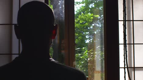 Locked-Off-View-Of-Silhouette-Of-Adult-Male-Sitting-And-Meditating-Indoors