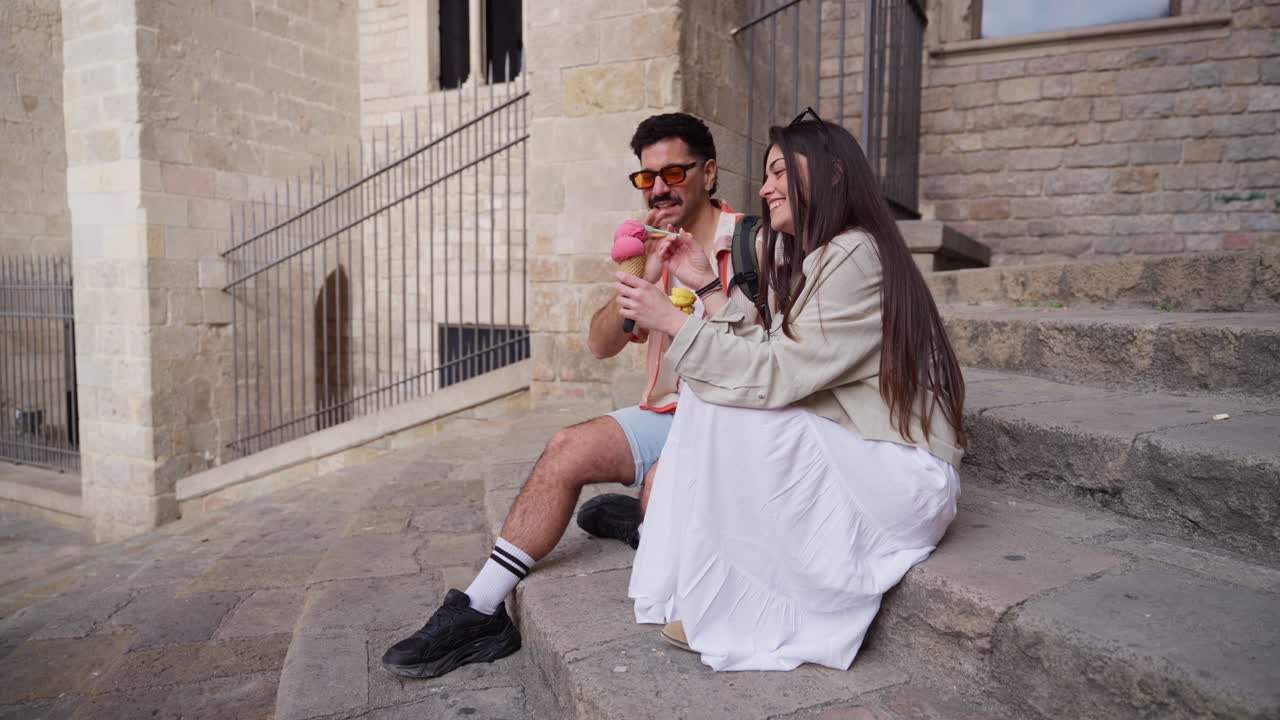 Coppia felice seduta sui gradini di pietra che mangia un gelato