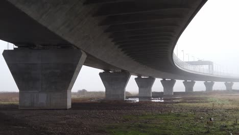 ghostly misty concrete support structure under motorway flyover panning right