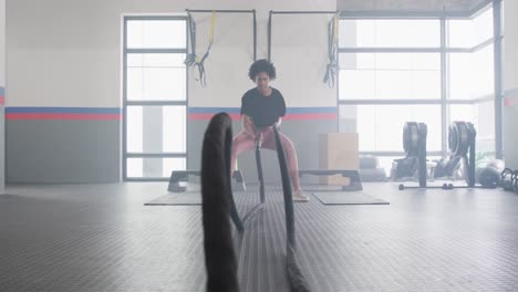 video de una mujer afroamericana decidida trabajando en un gimnasio con cuerdas de lucha