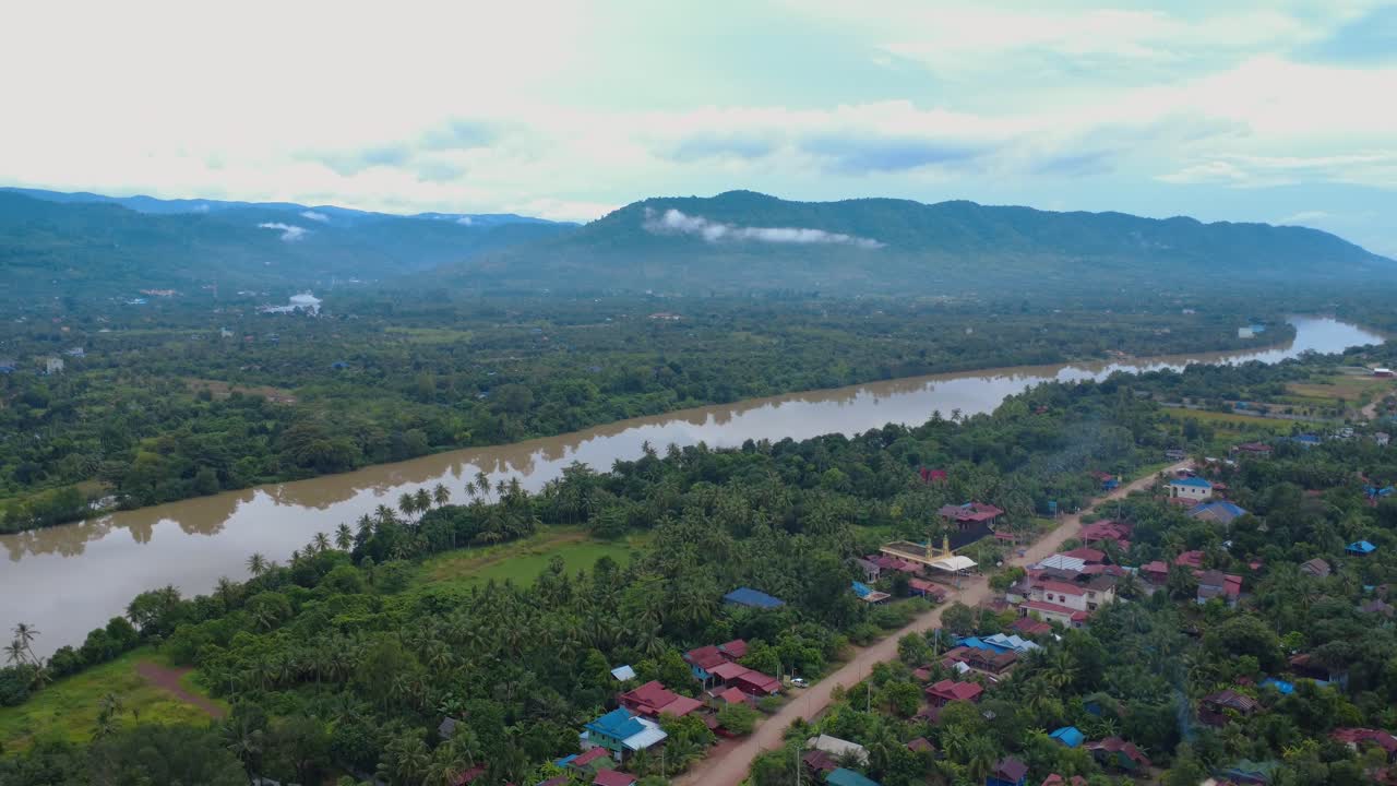 Aerial view of rural landscapes, river bends and country roads in Kampot Province near the Vietnam border, showing green farmland, scattered homes and peaceful tropical scenery at sunrise
