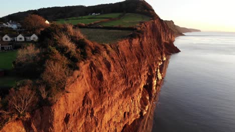 aerial shot of the red jurassic cliffs at sidmouth devon england at sunrise bathed in golden sunlight