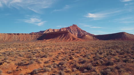 4k volando rápido sobre el desierto hacia una mesa de roca roja que revela una montaña en la distancia