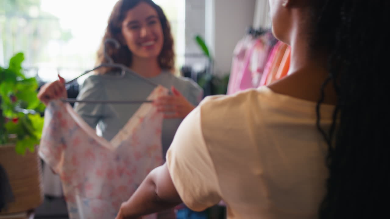 패션 상점에서 옷을 구입하는 두 친구가 옷의 비디오를 찍고 있습니다.