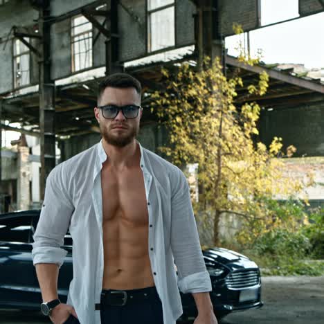 businessman with a handgun. young handsome man in shirt and glasses holds pistol in his hand. serious man with sportive body with a weapon outdoors.