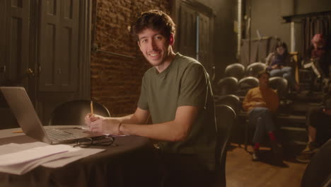 portrait of young playwright with laptop and papers in theater