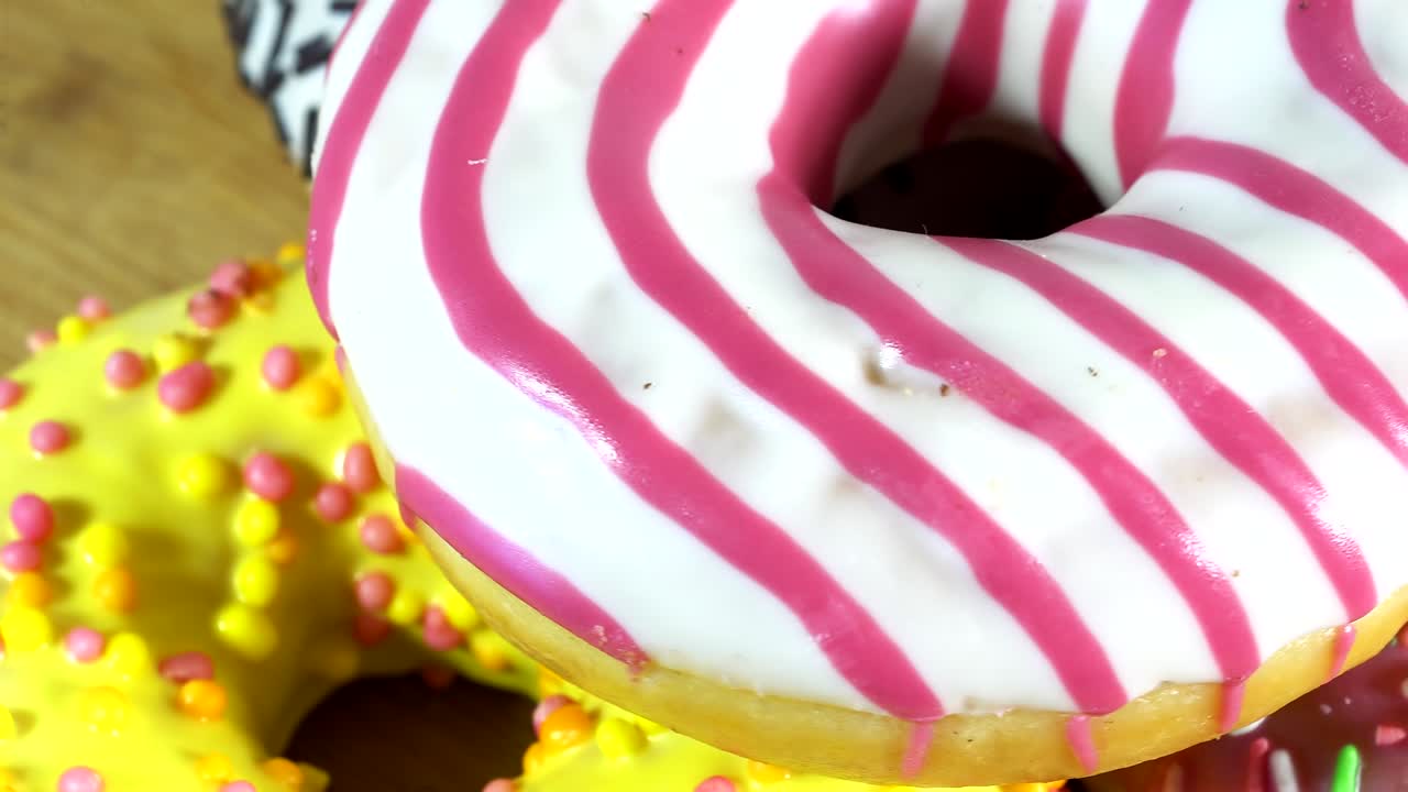 Rotating donuts with different fillings on the table. Delicious sweet donut rotating on a plate. Bright and colorful donut close-up macro shot spinning on a white background. Seamless loop.