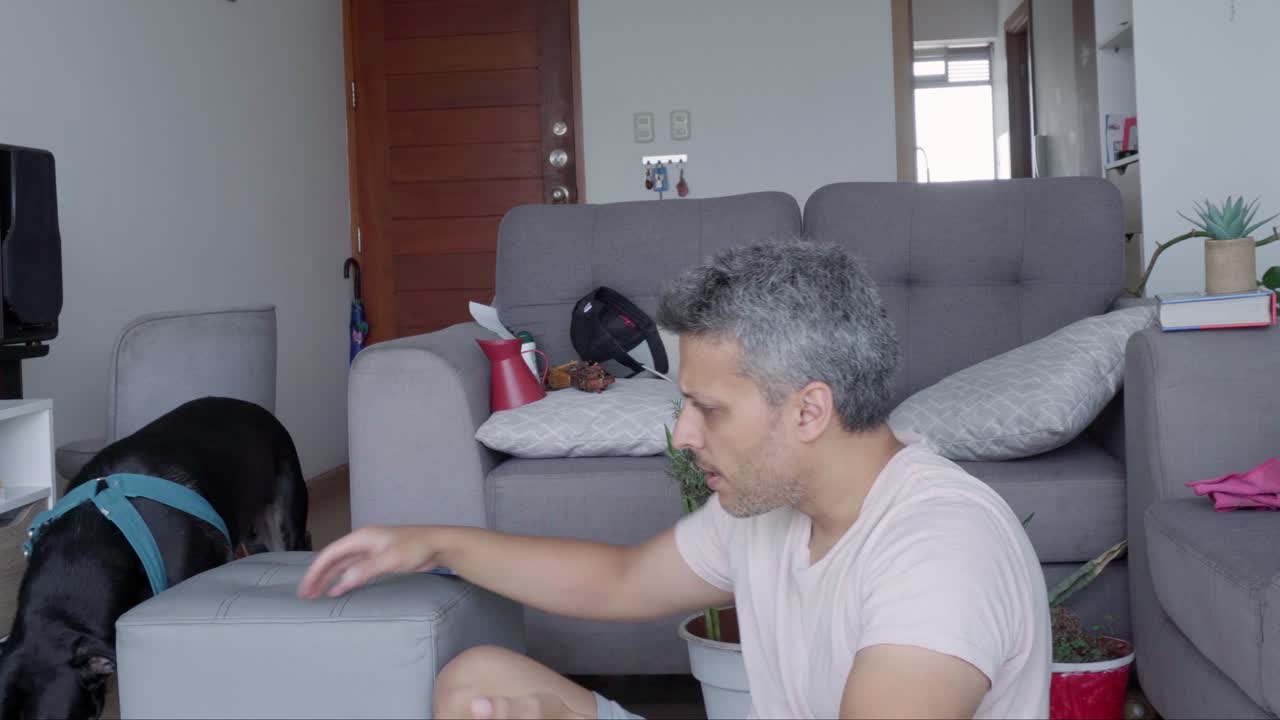 Homem brincando com seu cachorro na sala de estar.