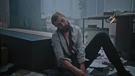 stressed man sitting on the floor in a messy office