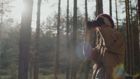 female explorer looking through binoculars on sunny day