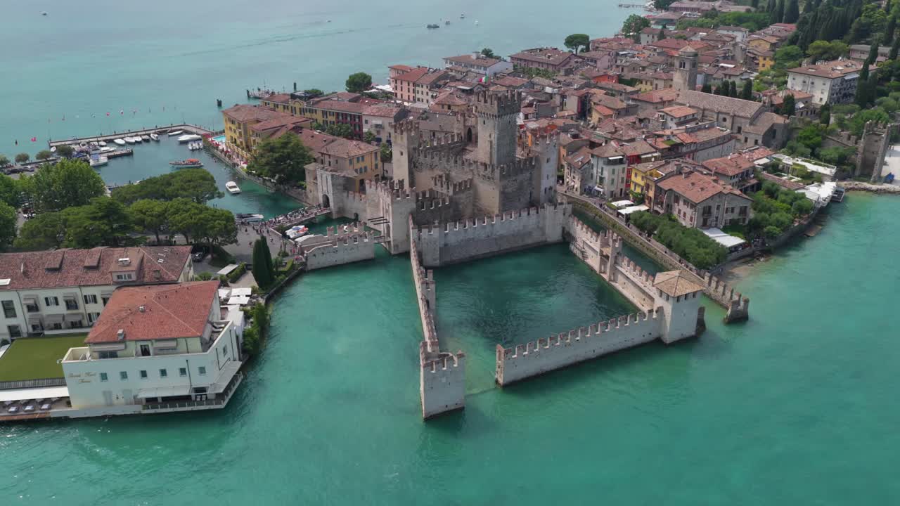 Aerial view of Scaliger Castle in Sirmione surrounded by turquoise waters of Lake Garda