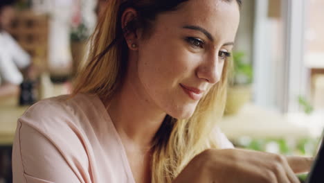 Beautiful-woman-using-ipad-tablet-computer-touchscreen-in-cafe