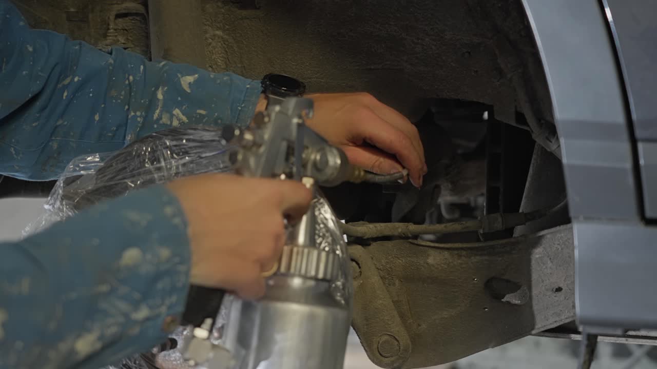 Mechanic uses cavity probe to spray lanolin rust prevention product inside hollow box sections behind protected brake disc