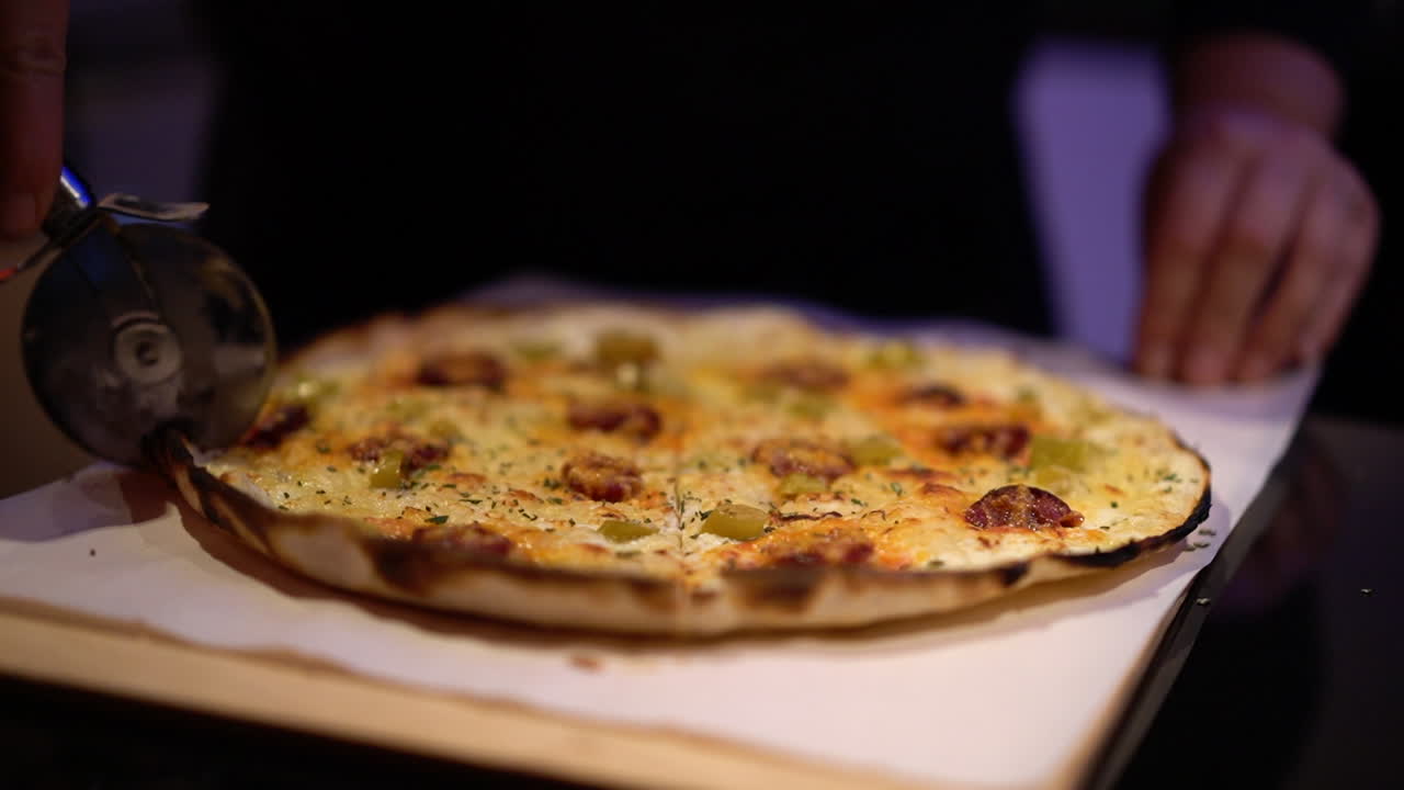 un hombre cortando una pizza con su cortador de pizza