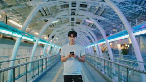 young man using smartphone on a modern urban walkway at night