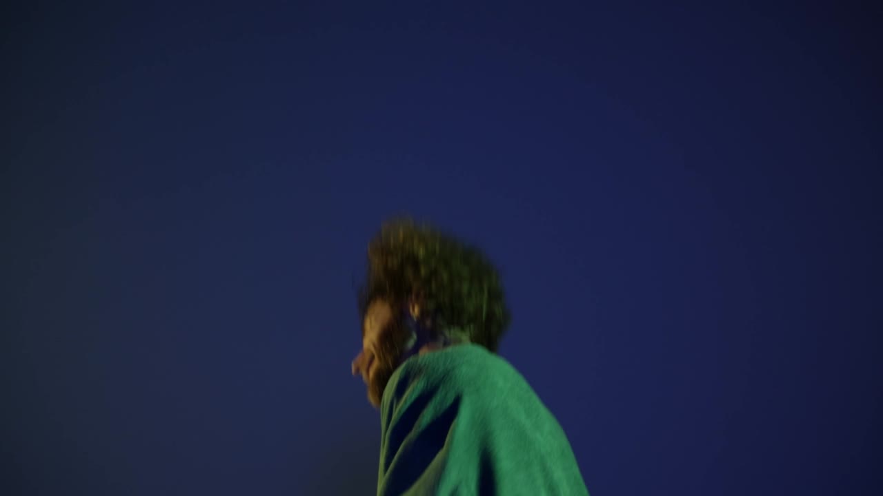 Giovane uomo entusiasta, ballerino hip-hop, che balla isolato su sfondo blu scuro in luce al neon. Arte della danza moderna, moda, gioventù, pubblicità, stile. 4K, video.