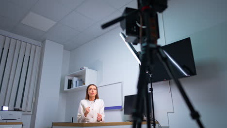 caucasian woman talks to camera gesturing with hands. professional camera filming a speaker. low angle view.