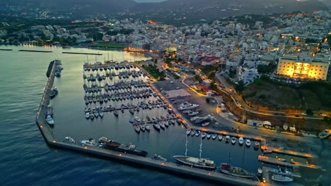 aerial view of a coastal city of agios nikolaos at dusk, illuminated marina