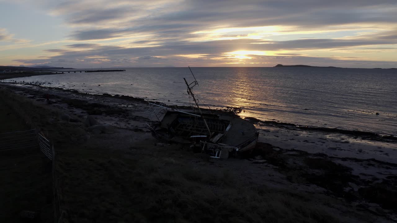 AERIAL - Shipwreck, boat on a beach at sunset in Kintyre, Scotland, reverse