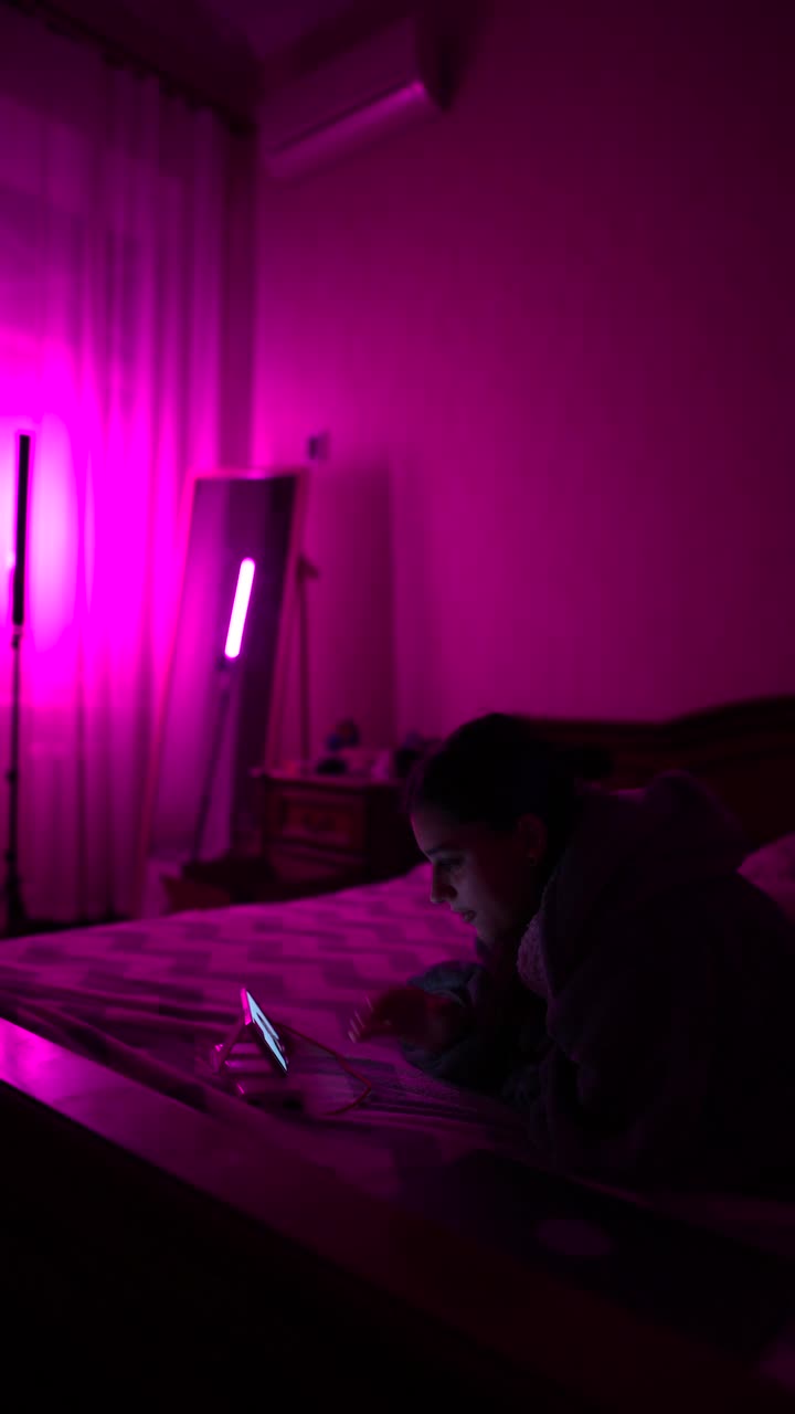 mujer acostada en la cama, viendo el teléfono en una habitación rosa