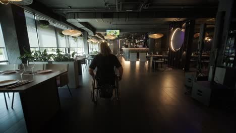 una mujer en silla de ruedas entra en un restaurante elegante y débilmente iluminado con decoración moderna y elementos artísticos. la escena destaca la accesibilidad en un entorno de comedor de moda, haciendo hincapié en la movilidad y el diseño inclusivo.