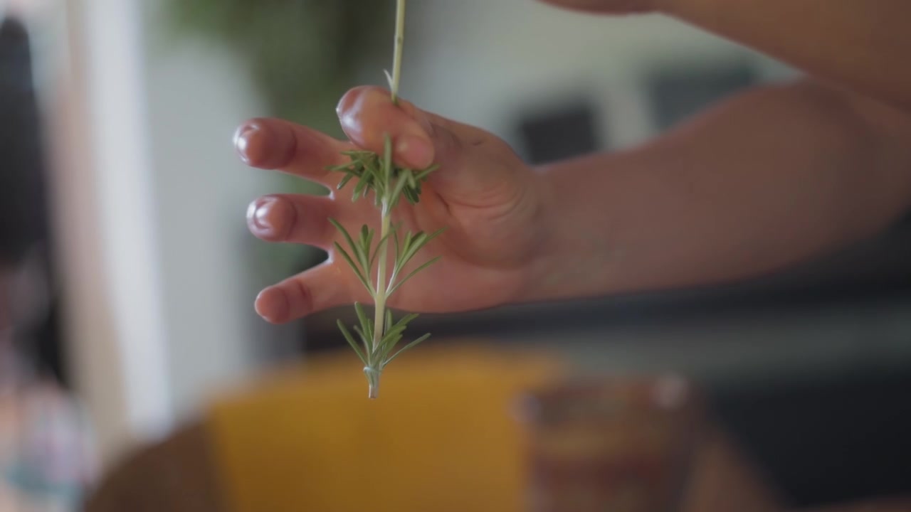 Chef peeling a rosemary stem into a bowl