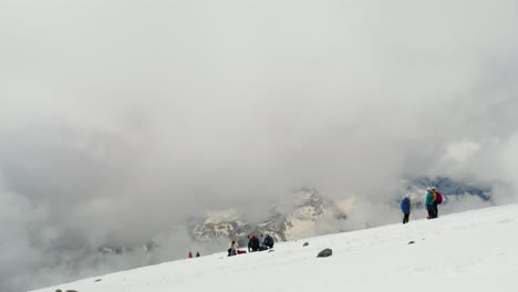 hikers on a snowy mountain summit in cloudy weather