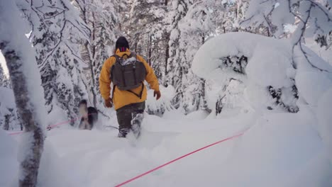Hombre-Caminando-En-La-Nieve-Profunda-Con-Perro-Mascota-Husky-Siberiano-Corriendo-En-Un-Día-De-Invierno