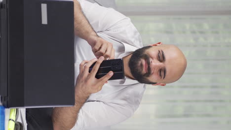 Vertical-video-of-Home-office-worker-man-having-problems-and-stress-on-the-phone.