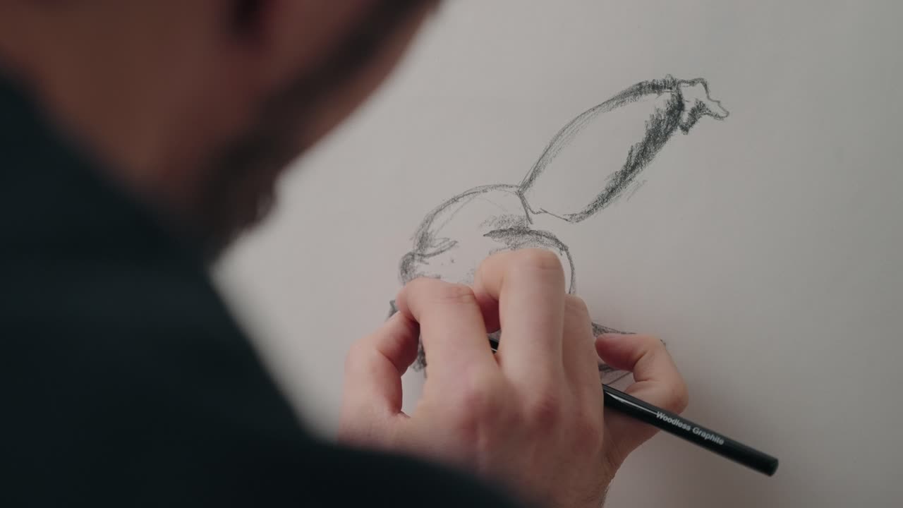 Close up of hand sketching a face and arm with pencil on paper