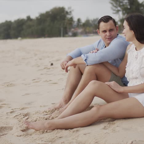 young lovers tourists sitting on beach