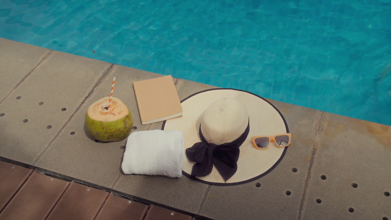 Hat, Drink, Towel and Notebook by Poolside at Resort