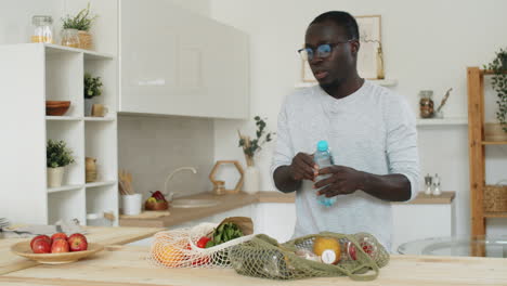 black man unloading groceries from net bags in kitchen