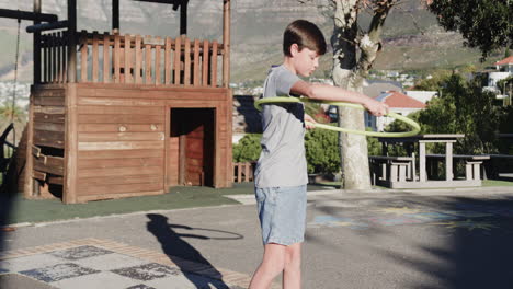 playing with hula hoop, boy enjoying outdoor activity at school playground