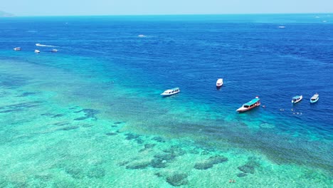 Peaceful-lagoon-with-anchored-boats-on-calm-clear-turquoise-water-full-of-coral-reefs-and-beautiful-patterns-of-pebbles-in-Malaysia