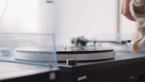 hand of woman wiping vintage turntable closeup. woman carefully wipes dust from turntable plate before putting disk with classical music. nostalgia concept