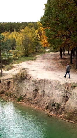 man walking along lake. aerial view of man walking along lake with forest vertical video