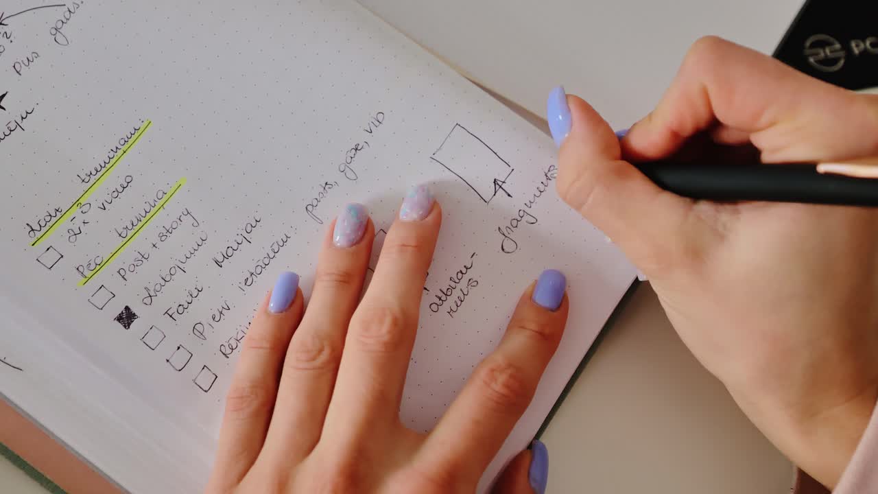 Shallow depth of field highlights glitter nails writing plans on notepad