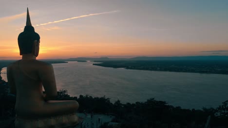 大きな仏像が穏やかに観察した、ラオスの大河メコン川に沈む見事な夕日の 4k 映像