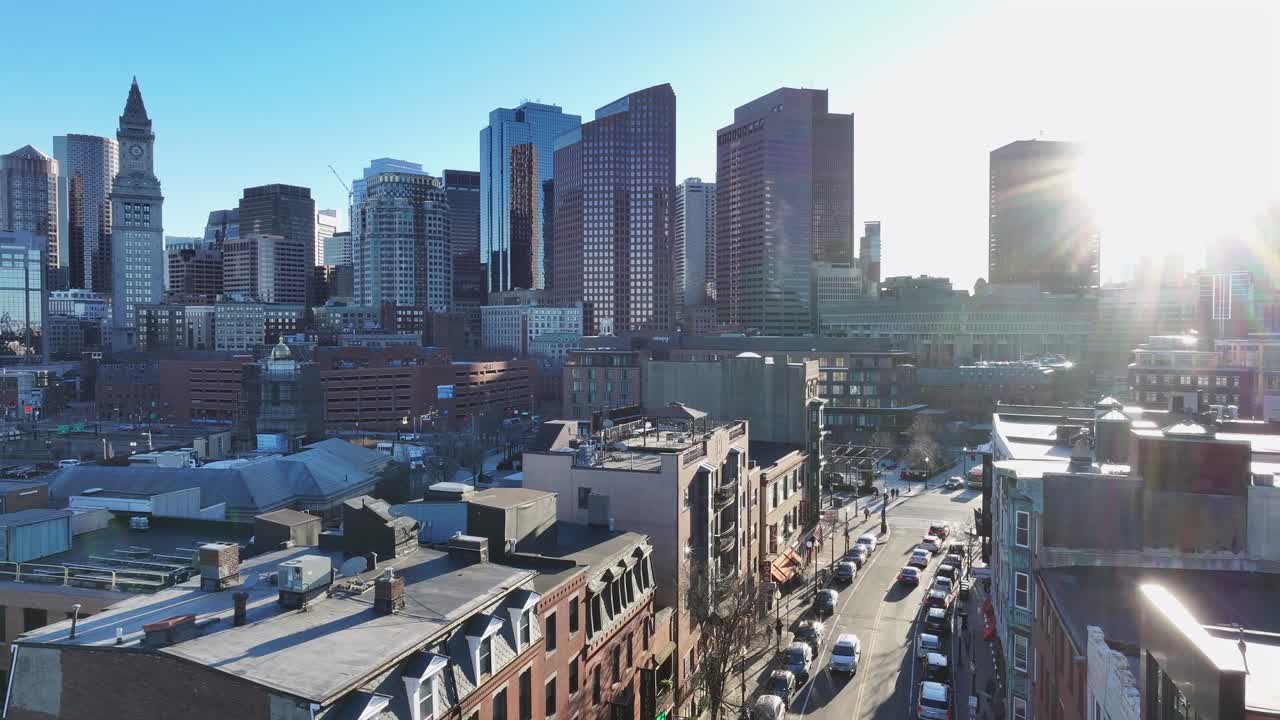 Boston’s skyline with sunlight reflecting off skyscrapers. Historic buildings line Hanover Street in the North End. Aerial reveal of Custom House Tower and downtown.