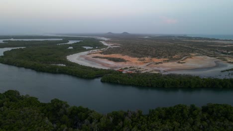 Drone-Vuela-Sobre-Un-Bosque-De-Manglares-Cruzando-Un-Extenso-Río-Estuario-Que-Revela-Una-Costa,-Hermoso-Horizonte-Con-Montañas-Tetas-De-María-Guevara,-Porlamar,-Isla-Margarita,-Venezuela