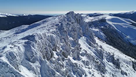 montañas bucegi cubiertas de nieve bajo un cielo azul claro, vista aérea panorámica a la luz del día